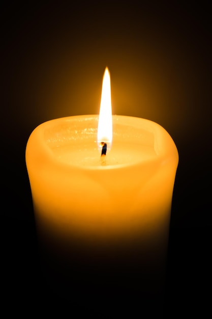 White candle burns on a black background Place for the text postcard