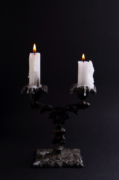 White candle in vintage candlestick on a black background