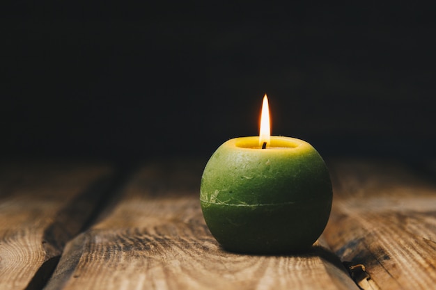 Una candela bianca con sfondo scuro - in un candelabro in legno.