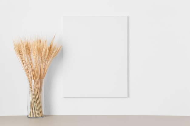 White canvas mockup on the wall with a dried flower decoration