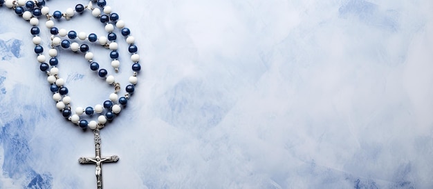 A white canvas with a painted background displaying a bluebeaded rosary viewed from the top