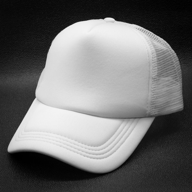 어두운 배경에 흰색 모자입니다. 디자인을위한 패션 모자입니다.