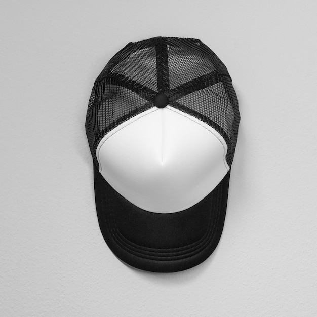 White caps with black nets on cement background. Top view angle of baseball cap.