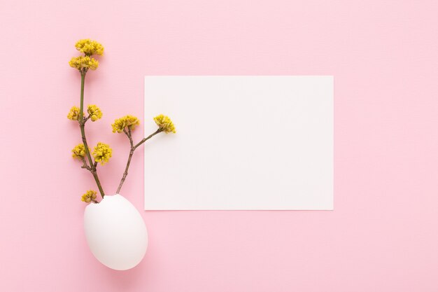 Mockup di carta bianca e ramo fiorito all'interno del guscio d'uovo di pasqua su sfondo rosa. cartolina d'auguri di giorno di pasqua.