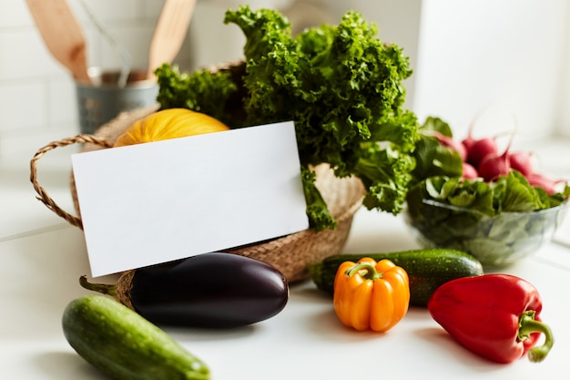 White card on the table with fresh appetizing vegetables