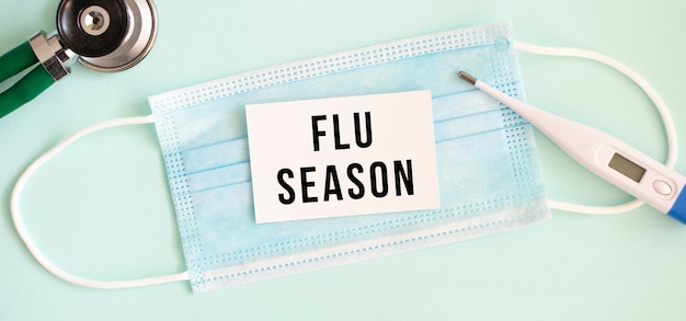 Photo white card with the inscription flu season on a medical protective mask