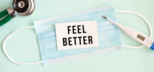 사진 의료 보호 마스크에 비문 feel better와 흰색 카드. 의료 개념.