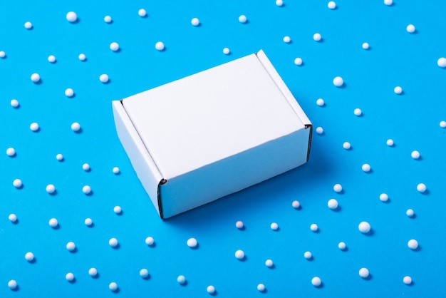 Photo white cardboard box decorated with white balls on blue background