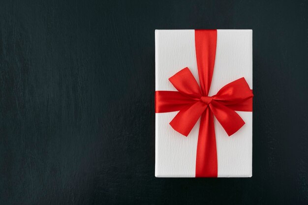 White cardboard box with red ribbon on black