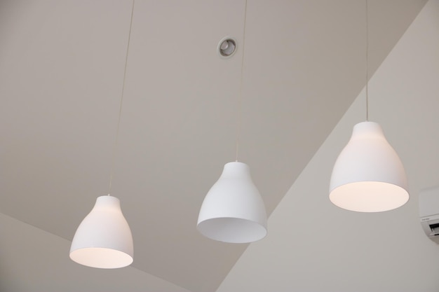 A white ceiling with three white lamps hanging from the ceiling.