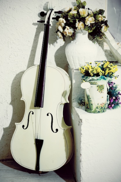 White cello with flowers in white room