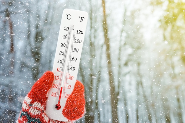 Foto termometro bianco con scala celsius e fahrenheit in mano temperatura ambiente meno 18 gradi celsius