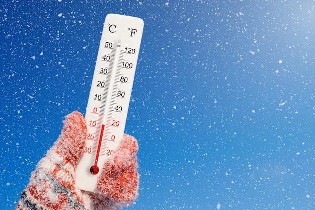 Foto termometro bianco su scala celsius e fahrenheit in mano temperatura ambiente meno 7 gradi celsius