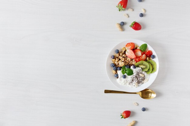 White ceramic bowl of homemade granola with yogurt fresh berries and fruits