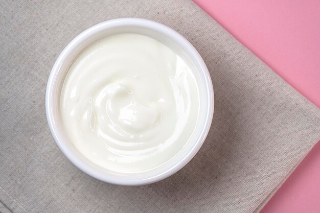 Photo white ceramic bowl with fresh sour cream yogurt on a table top view