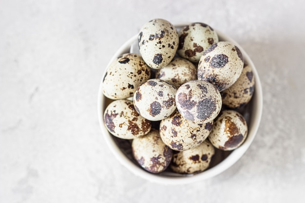 White ceramic bowl with quail eggs, light grey stone