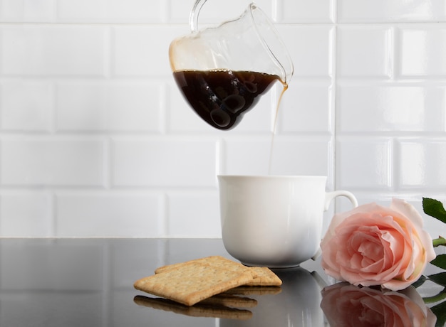 Photo white ceramic cup with pieces of biscuit and  one peach color rose