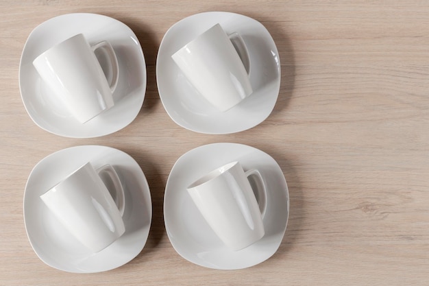 White ceramic cups and plates on wooden background image