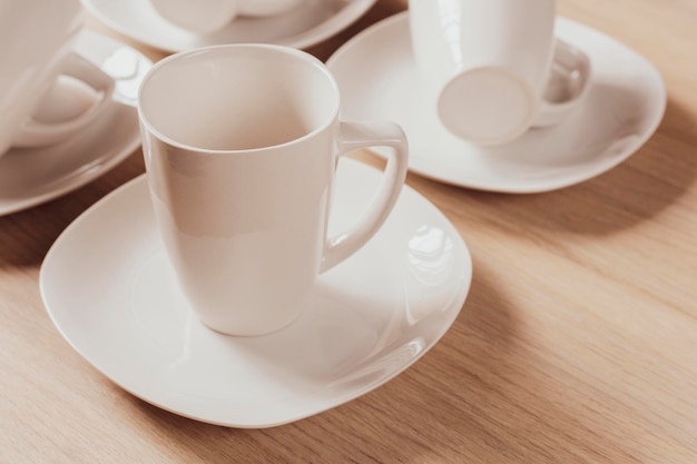 White ceramic cups and plates on wooden background image