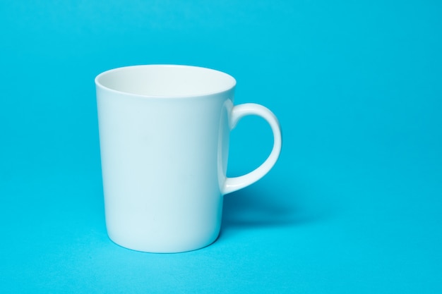 White ceramic glass isolated on a blue wall. copy space and Simplicity