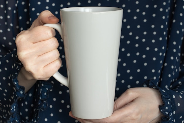 Foto tazza da caffè in ceramica bianca con latte nelle mani della donna