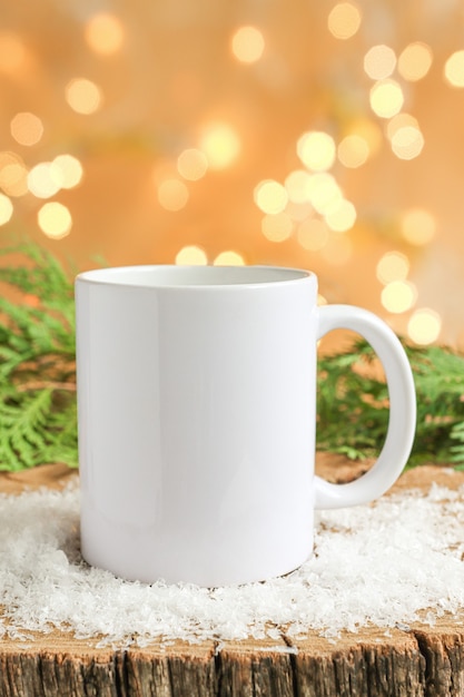 White ceramic mug on a wooden table with pieces of snow and ice mockup for copy space