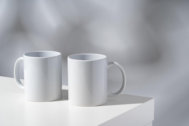 White ceramic mugs on gray background with shadows