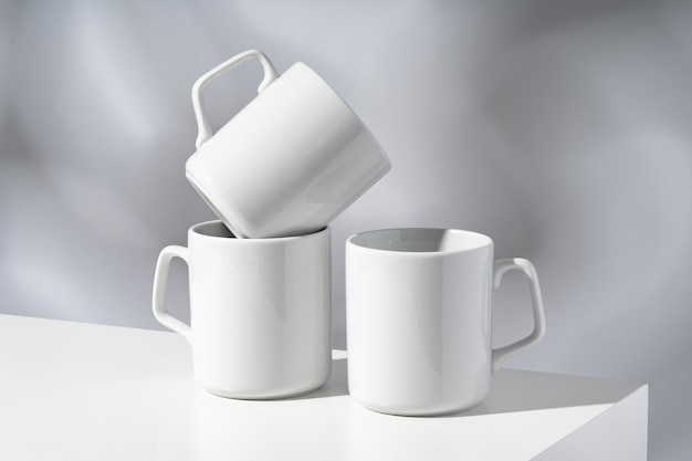 White ceramic mugs on gray background with shadows