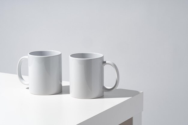 White ceramic mugs on gray background with shadows