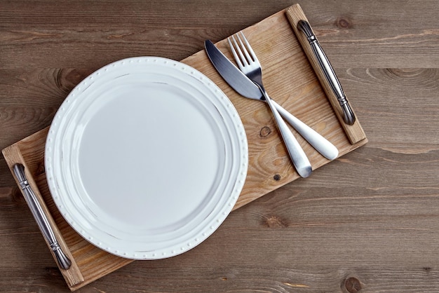 White ceramic plate and cutlery tray on a grunge wooden table