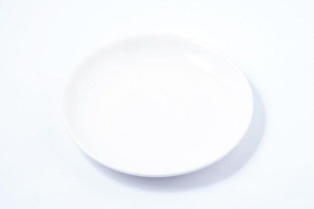 White ceramic plate on a white table. For food, advertising space.