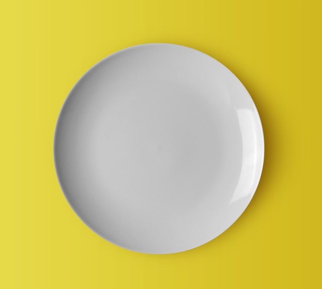 White ceramic plate on yellow background