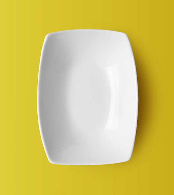 White ceramic plate on yellow background