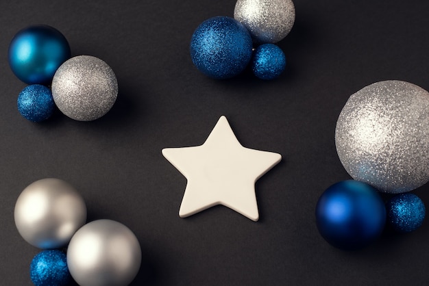 White ceramic star and Christmas balls of a different color on a dark background