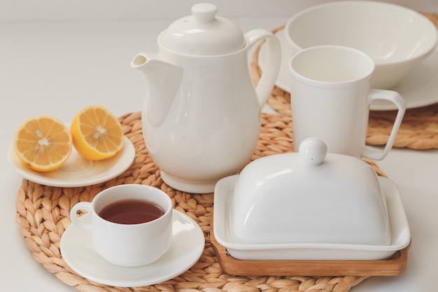 White ceramic tableware, fibre braided round placemat and cutlery set on white background. Scandinavian style