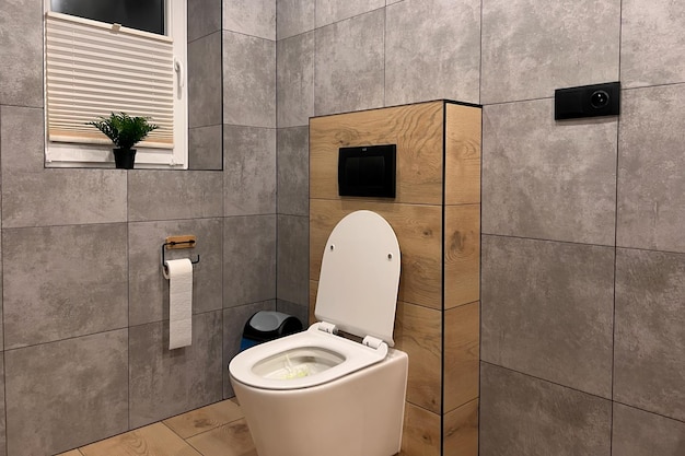 A white ceramic toilet in a modern bathroom The toilet has a closed bowl and a seat with a flush The bathroom has a tiled wall and floor