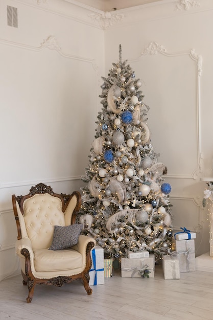 white chair by the Christmas tree. decorated Christmas tree. brick wall. new year's interior. design