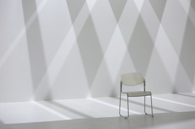 White chair in front of diamond shape shadow wall