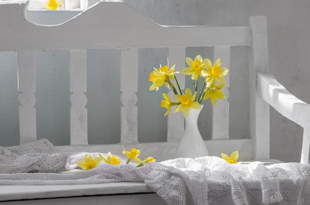 Photo a white chair with a vase of daffodils on it