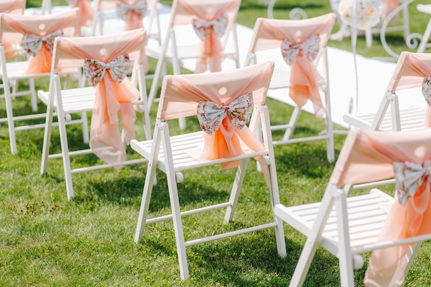 White chairs decorated with bows are on the nature