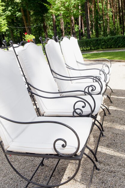 White chairs stand in the rows before wedding altar in park