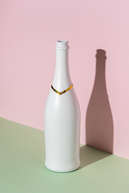 Белая бутылка шампанского на яркой поверхности.