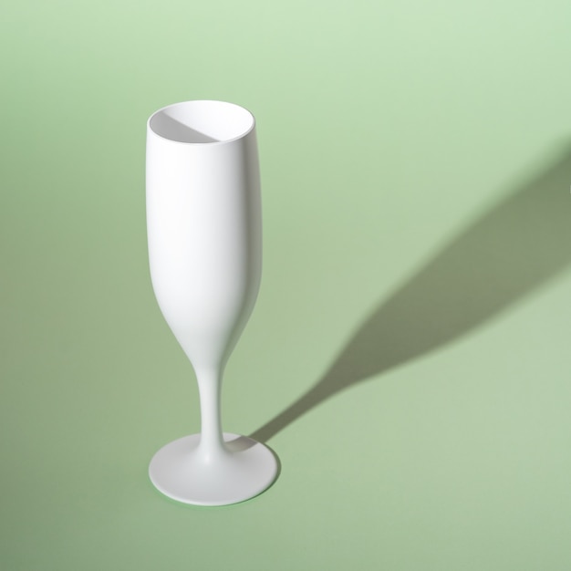 White champagne glass on green background.