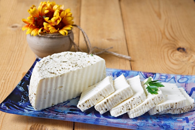 White cheese on a blue plate on a wooden background