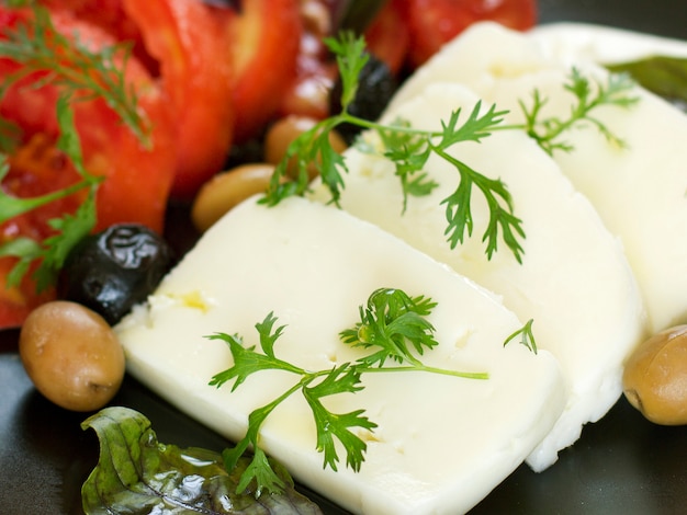 White cheese with tomatoes, green and black olives, basil, coriander and olive oil