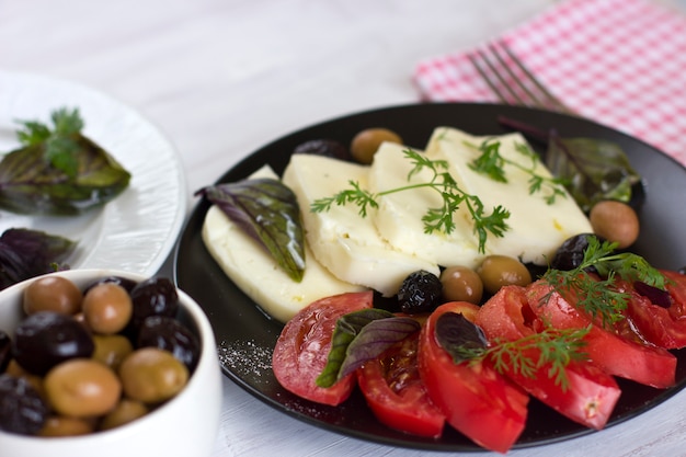 White cheese with tomatoes, green and black olives, basil, coriander and olive oil 