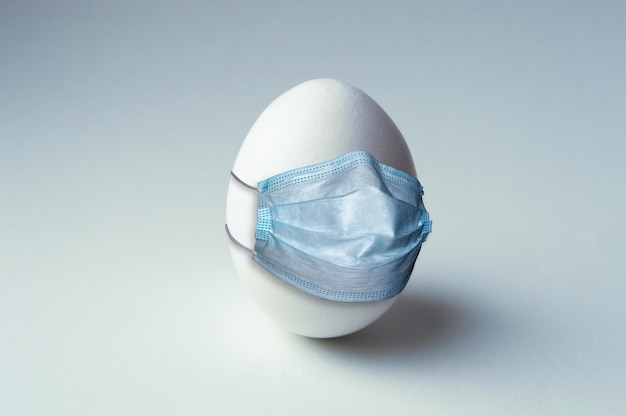 White chicken egg in medical mask