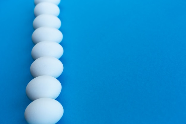 White chicken eggs on a blue background lined with a line