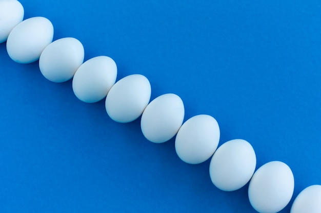 White chicken eggs on a blue background lined with a line