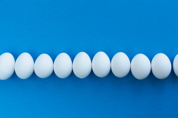 White chicken eggs on blue lined with a line